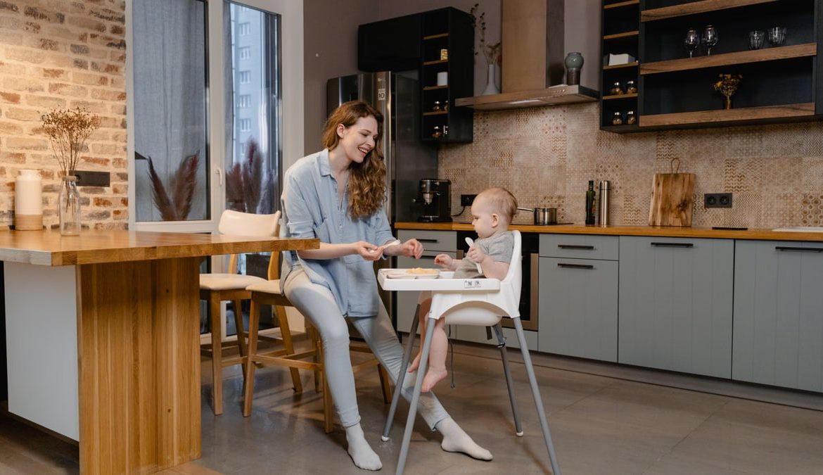 A mother and her baby enjoy bonding time in a cozy modern kitchen.